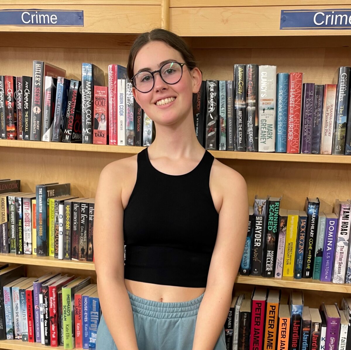 Teenage girl smiling in front of book shelves