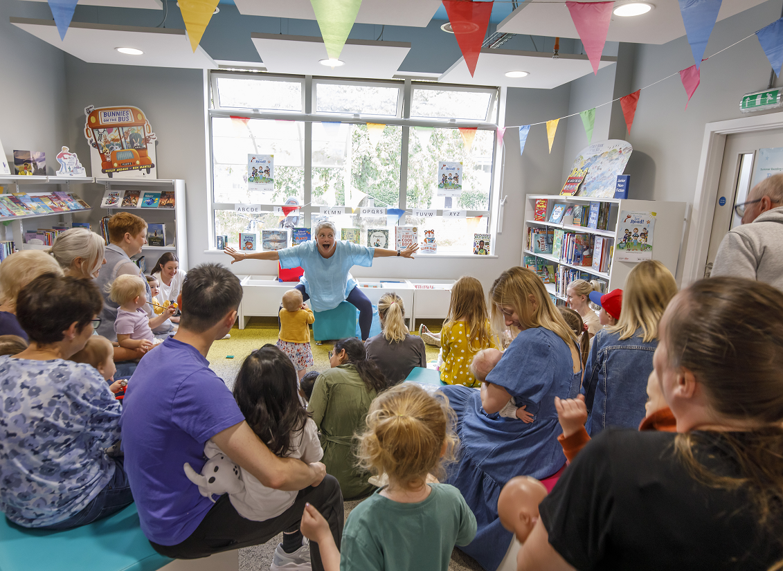 Lady telling a story to a group of young children and their parents