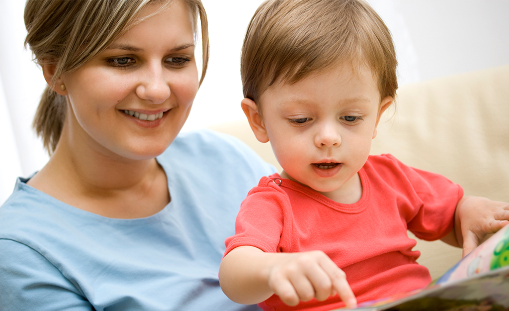 Young boy looking at a book with a woman